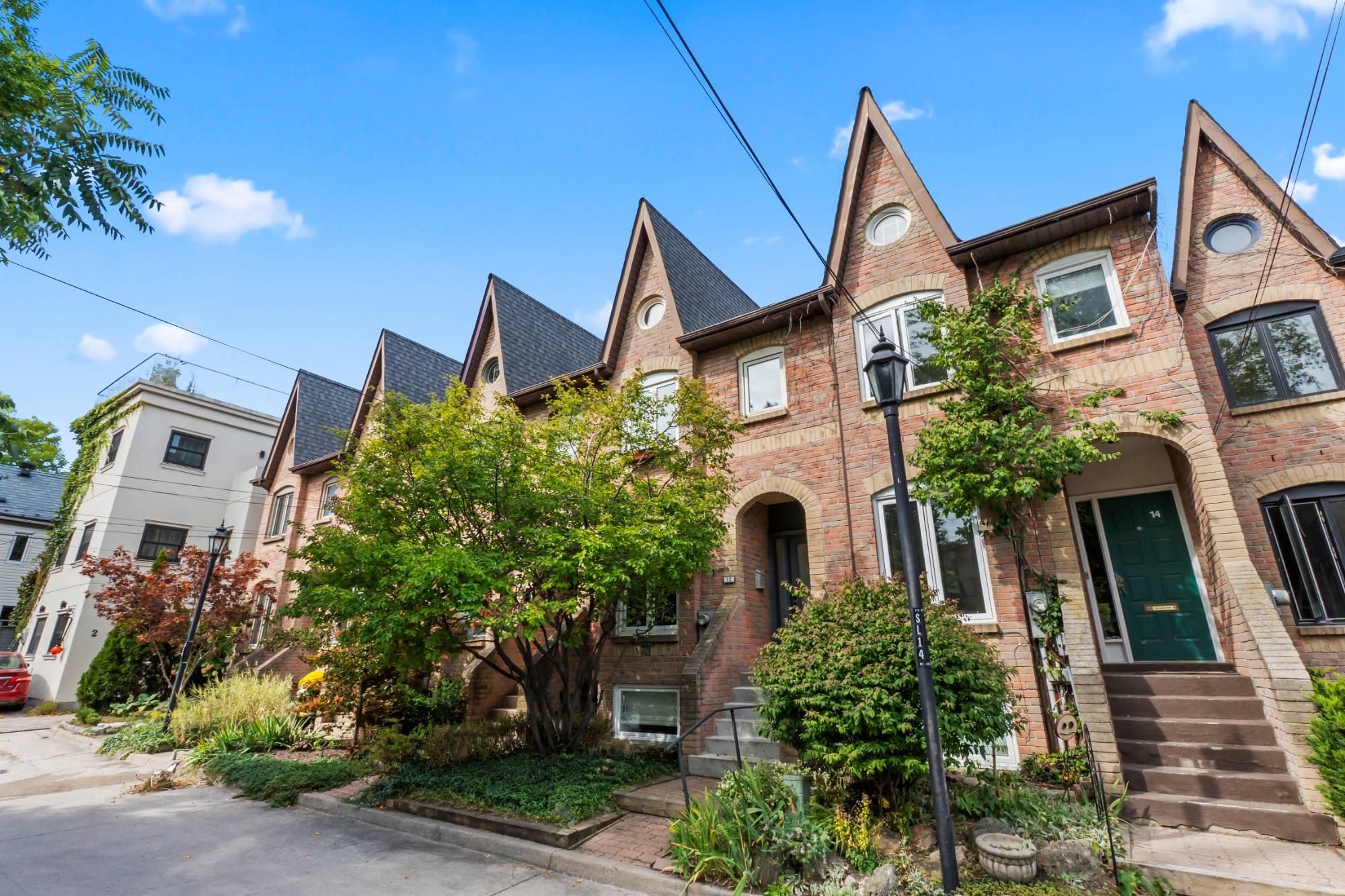 The row of red-brick Victorian-style townhouses on St James Court, with steep pointed gables and round attic windows, under a blue sky