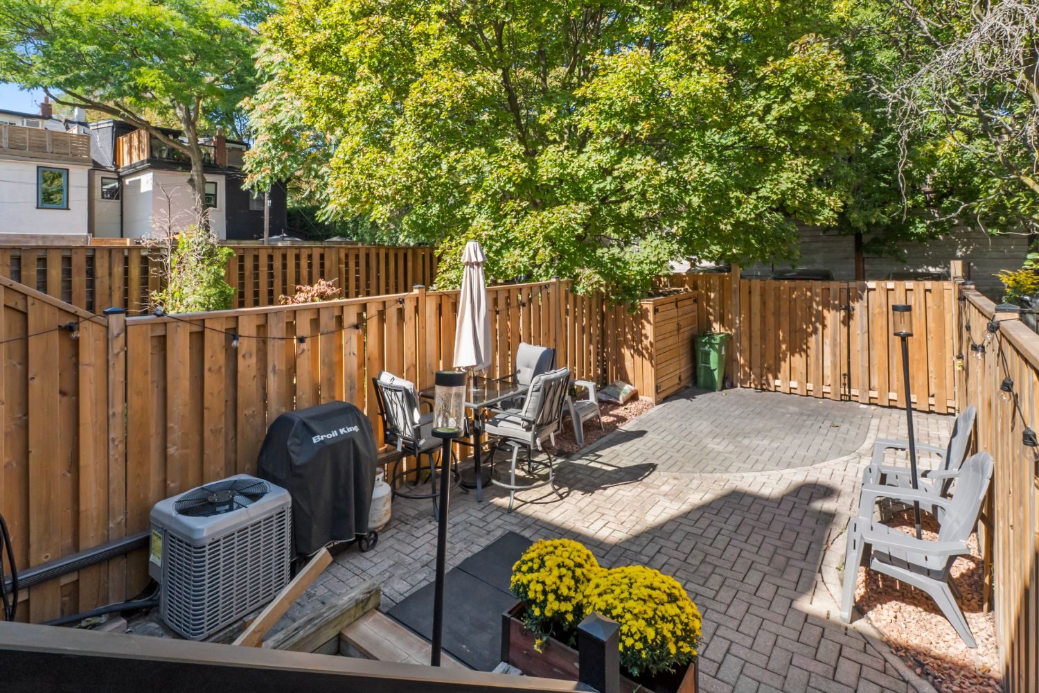 Fenced backyard with an interlocking-brick patio, dining set and mature trees