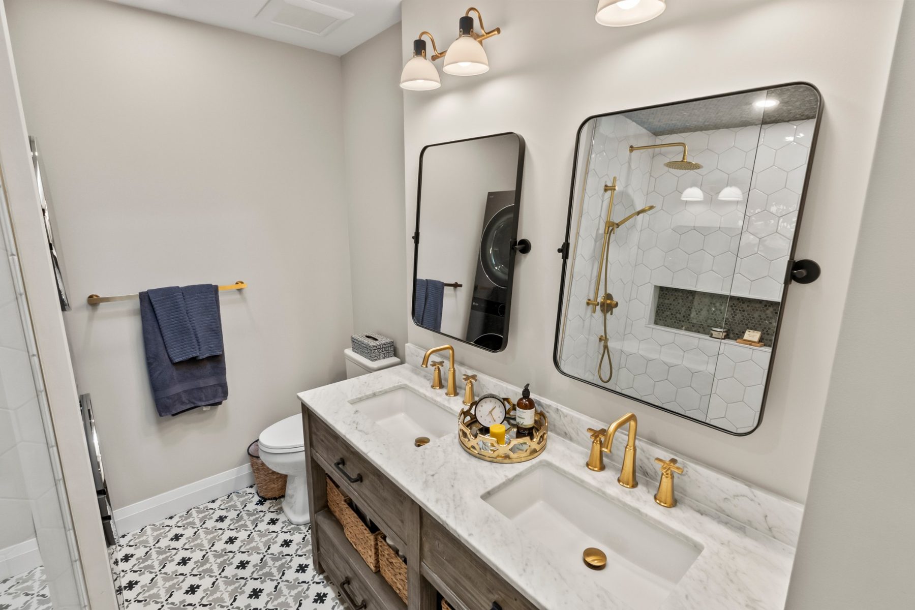 Bathroom with double marble vanity, brass fixtures and a glass hexagon-tile shower