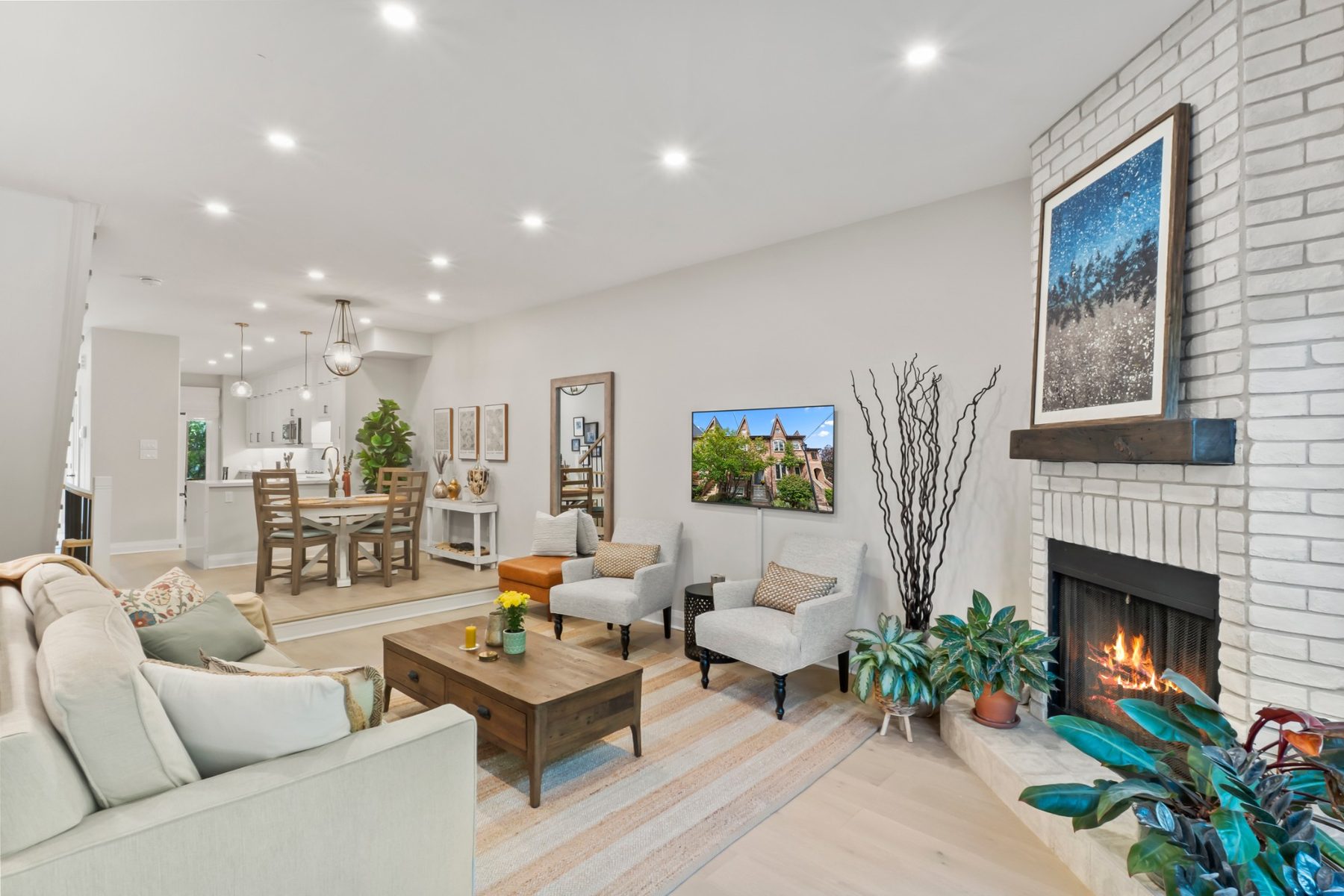 Main-floor living room with a white-brick wood-burning fireplace, open to the dining area and kitchen